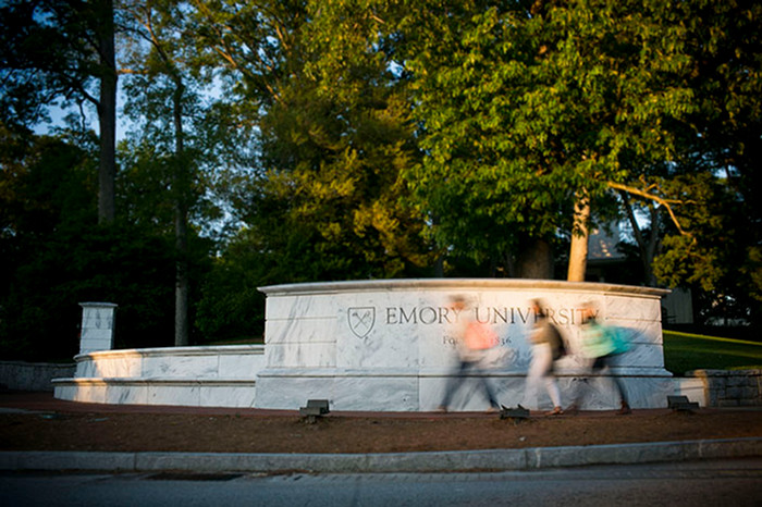 marble wall that says emory with students walking by